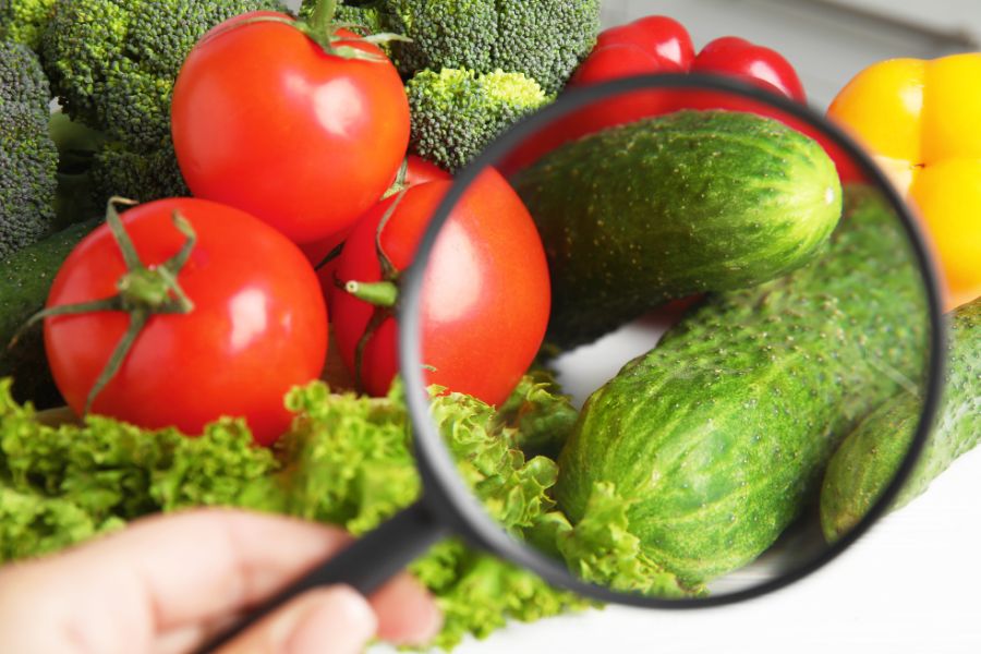 woman using magnifying glass to check vegetables