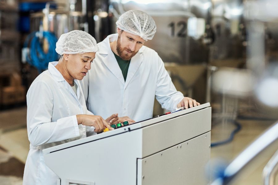 two workers wearing lab coats operating checkweigher